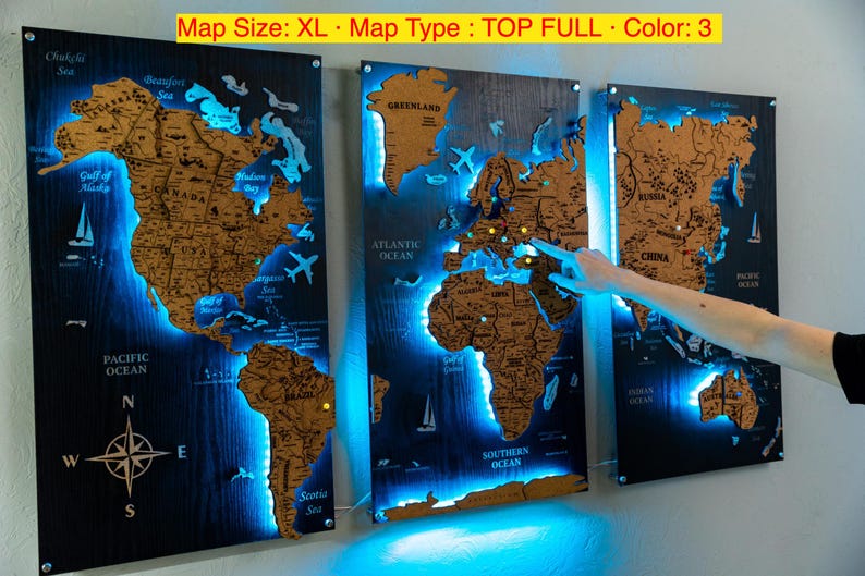 a person pointing at a three-panel world map that is illuminated with blue light, creating a visually striking and unique display.