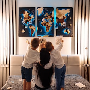 A family of four, including two children and a dog, are gathered around a large world map on the wall, pointing at various locations and landmarks.