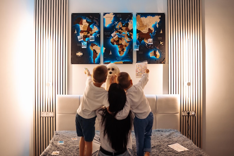 A family of four, including two children and a dog, are gathered around a large world map on the wall, pointing at various locations and landmarks.