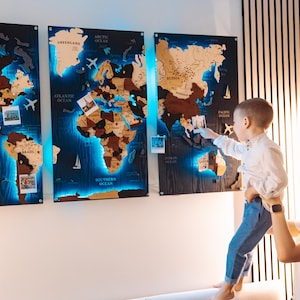 A woman holds a young child in front of a large world map with three panels, each depicting different regions of the world.