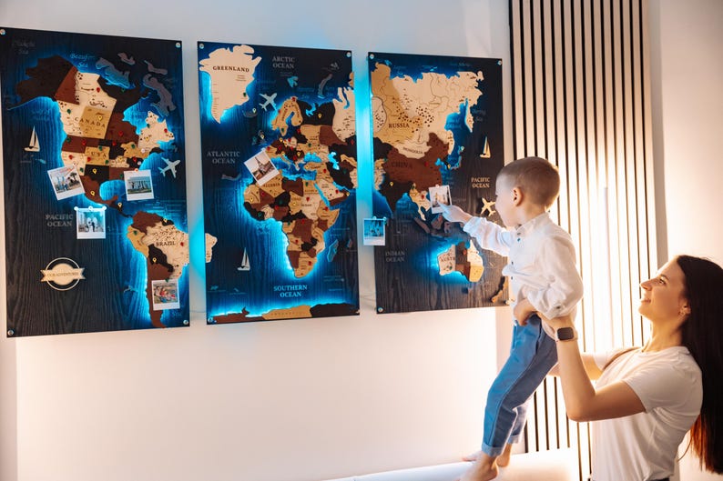 A woman holds a young child in front of a large world map with three panels, each depicting different regions of the world.