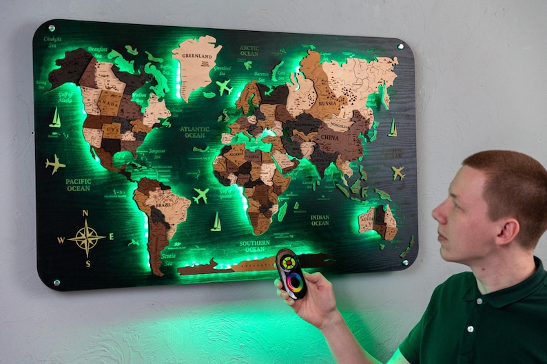 A person is standing in front of a large world map that is illuminated with green lights, creating a unique and visually striking display.