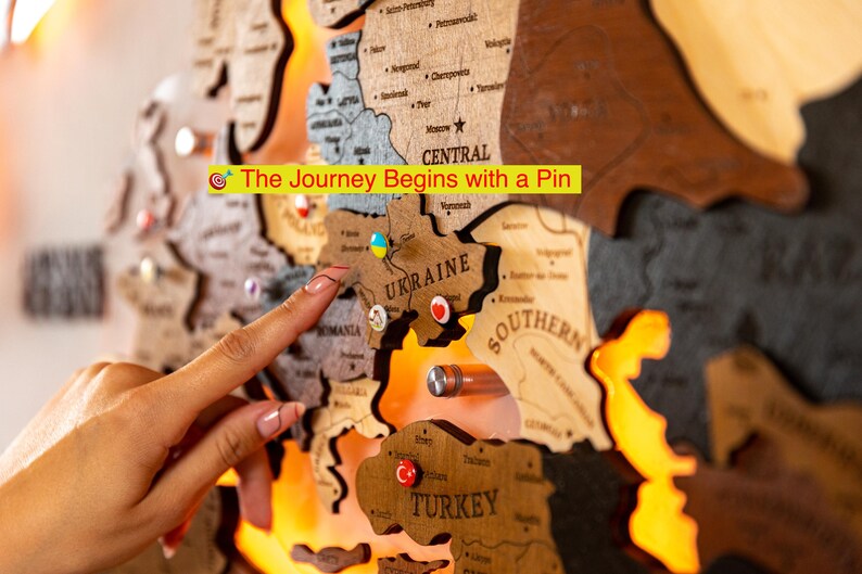 A hand is pointing at a wooden map of Europe, with the word "TURKEY" visible on one of the map pieces.