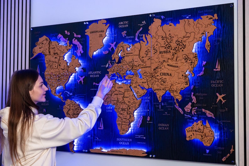A woman is pointing at a large world map that is illuminated with blue lights, creating a visually striking and unique display.