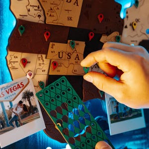 A person's hand is holding a green and blue puzzle piece in front of a map of Las Vegas, with a photograph of a couple on the map.