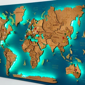 May include: A wooden world map with a teal background and illuminated green LED lights. The map features countries in a light brown color, with pins marking locations. Decorative airplane and sailboat cutouts are also included.
