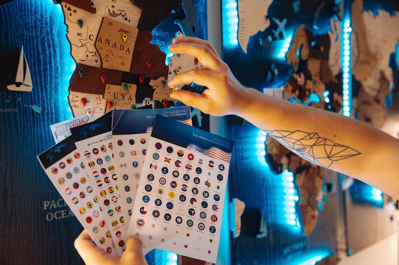 A person's hand is holding a stack of cards with various country flags, against a backdrop of a world map with blue lighting.