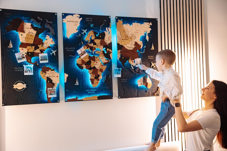 A woman holds a young child in front of a large world map with three panels, each depicting different regions of the world.