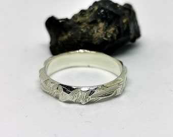 May include: A silver ring with a textured, hammered finish. The ring is simple and elegant.