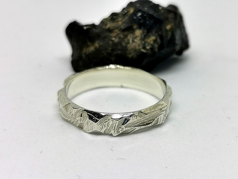 K&ouml;nnte beinhalten: Ein silberner Ring mit einer strukturierten, geh&auml;mmerten Oberfl&auml;che. Der Ring ist schlicht und elegant.