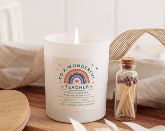 Puede incluir: Vela blanca con un arcoíris y el texto "To a Wonderful Teacher" en la etiqueta. La etiqueta también incluye el texto "Thanks for being the brightest teacher ever!" y "Love from AVA". La vela tiene un aroma a lavanda y arde durante 25 horas.