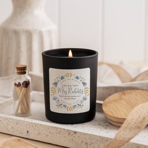 May include: Black candle in a glass jar with a floral design label that says "Thank You Mrs. Roberts You're the best teacher ever! Love from Oscar".