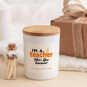 May include: White candle with a bamboo lid and a label that reads "I'm a teacher. What's your superpower?" The candle has a lavender scent and a burn time of 25 hours.