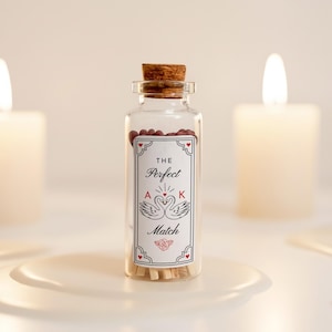 May include: A clear glass bottle with a cork stopper, filled with matches and red-tipped match heads. The label reads "The Perfect Match" with swan illustrations. Two lit candles are in the background, creating a soft, warm ambiance.