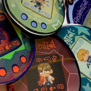 May include: Five colorful, round, plastic keychains with a pixelated design inspired by the video game Resident Evil. Each keychain features a different character from the game, including a zombie, a monster, and a human character. The keychains are all in different colors, including green, blue, purple, and red.