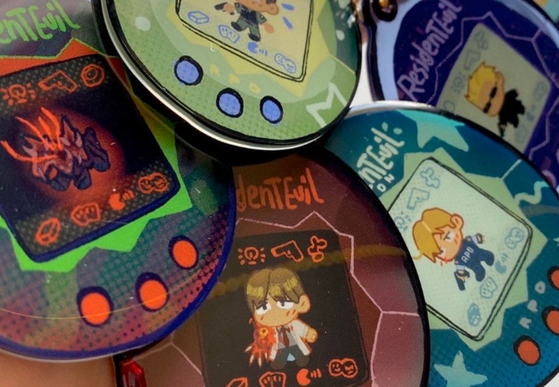 May include: Five colorful, round, plastic keychains with a pixelated design inspired by the video game Resident Evil. Each keychain features a different character from the game, including a zombie, a monster, and a human character. The keychains are all in different colors, including green, blue, purple, and red.