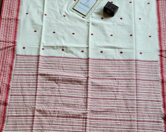 May include: Cream-colored textile with a red border and accents. The fabric features small red floral patterns and horizontal stripes. A small framed card with the text "monbahari" is visible, along with a small, dark wooden block.