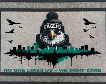 May include: A rectangular doormat featuring a stylized eagle wearing a beanie with the word "EAGLES" and sunglasses. The design includes a cityscape silhouette, birds, and the text "NO ONE LIKES US - WE DONT CARE."
