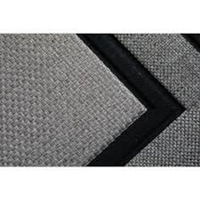May include: A gray woven rug with a black border. The rug has a textured surface and a subtle pattern.