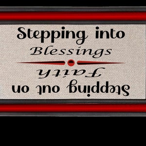 May include: A framed sign with a red and black border. The sign has a beige background with the text "Stepping into Blessings with Faith" written in black cursive.