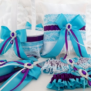 May include: Wedding ceremony set with teal and purple ribbon, lace, and jeweled accents. Includes a ring pillow, flower girl basket, cake knife and server, and a garter.
