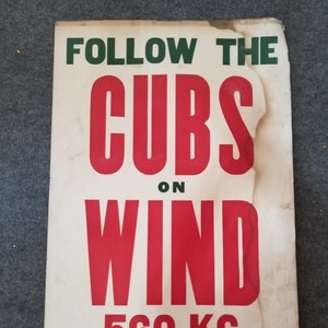 May include: A vintage white poster with green and red text that reads "Follow the Cubs on WIND 560 KC" and "Compliments Your Sinclair Dealer".