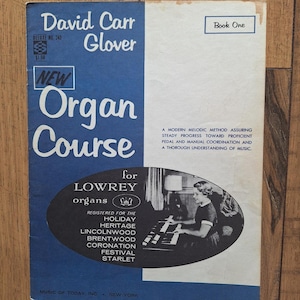 May include: A blue and white book cover with the title "David Carr Glover New Organ Course for Lowrey organs" and a photo of a woman playing a Lowrey organ. The book is for the Holiday, Heritage, Lincolnwood, Brentwood, Coronation, Festival, and Starlet organs. The book is Deluxe No. 243 and costs £1.50. Book One.