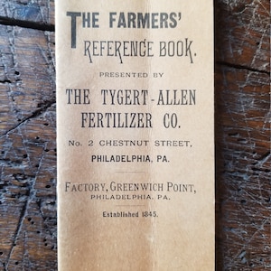 May include: A vintage book cover with the title "The Farmers' Reference Book" presented by "The Tygert-Allen Fertilizer Co.". The cover is brown with black text and the company's address is listed as "No. 2 Chestnut Street, Philadelphia, PA."