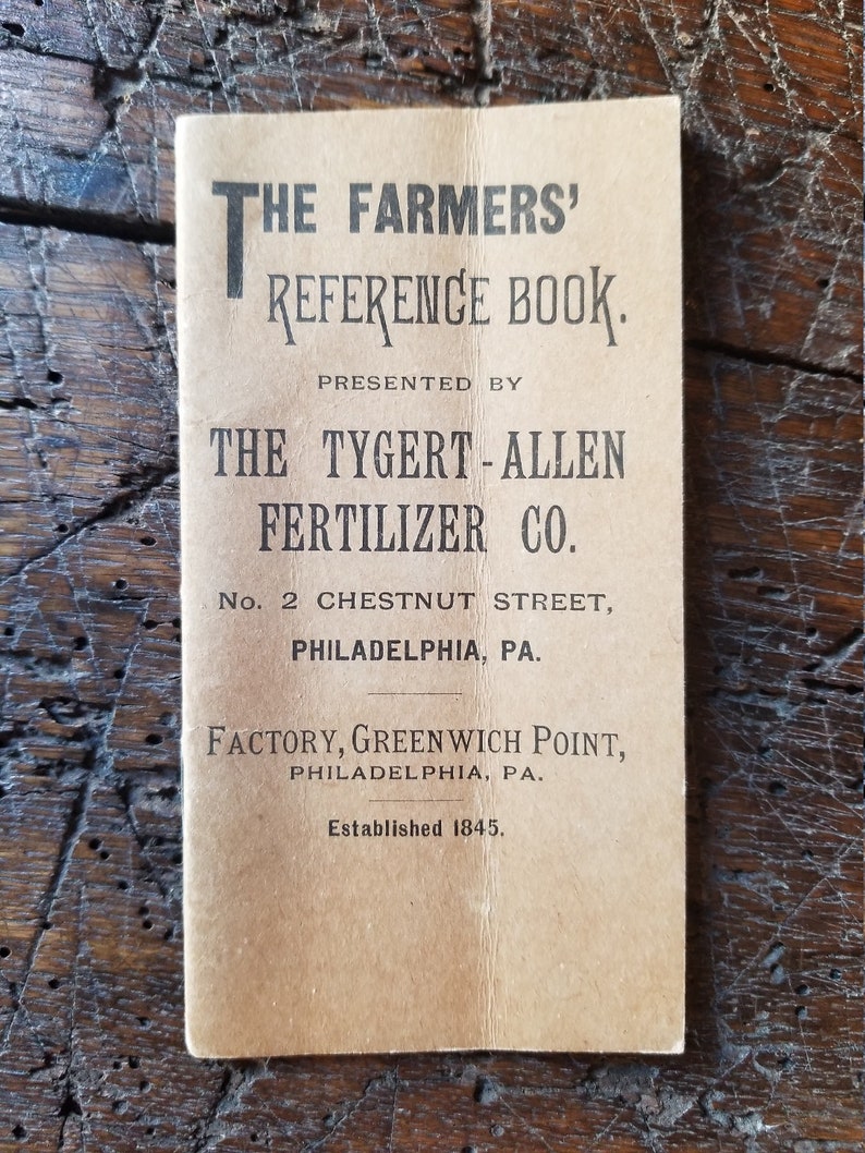 May include: A vintage book cover with the title "The Farmers' Reference Book" presented by "The Tygert-Allen Fertilizer Co.". The cover is brown with black text and the company's address is listed as "No. 2 Chestnut Street, Philadelphia, PA."