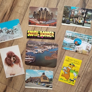 May include: A collection of vintage postcards featuring various subjects, including a view of Mount Rushmore, a church, a beach scene, a dog, and a cartoon character. The postcards are in various colors and styles.