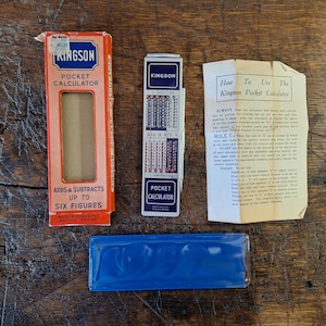 May include: A vintage Kingson pocket calculator set including a red cardboard box with white text, a slim metal calculator with numerical columns, a blue plastic protective case, and a folded paper instruction sheet titled How To Use The Kingson Pocket Calculator.