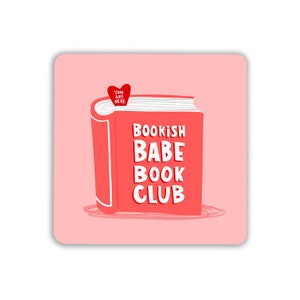 May include: A pink background with a red book that says "Bookish Babe Book Club". A small red heart with the text "You Are Here" is on top of the book.