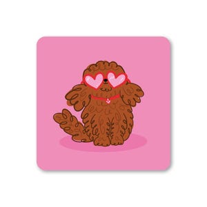 May include: A square, pink coaster featuring a cartoon dog with brown fur and heart-shaped sunglasses. The dog has a small white heart on its chest. The coaster is a fun, whimsical design.