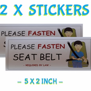May include: Two 5x2 inch white stickers with a cartoon illustration of a person wearing a seatbelt. The text on the stickers reads "Please fasten seat belt - Required by law - "