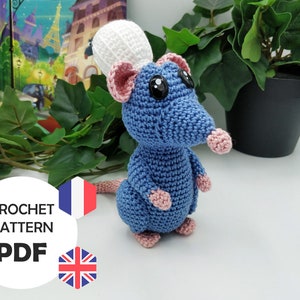 May include: A blue crochet rat wearing a white chef's hat, with pink ears, nose, and feet. The rat has large black eyes and a pink tail. The image includes the text "CROCHET PATTERN PDF" with the French and British flags.