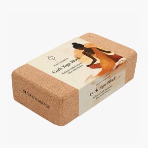 K&ouml;nnte beinhalten: Ein Kork-Yogablock mit dem Text "SHAKTI WARRIOR" und "Cork Yoga Block: Balance with Purpose, Rise with Power" auf der Seite. Der Block ist braun und hat eine nat&uuml;rliche Korkstruktur.