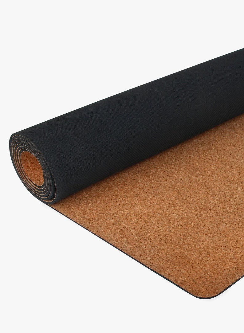 May include: A rolled-up black yoga mat with a cork bottom. The mat is partially unrolled, revealing the cork surface.