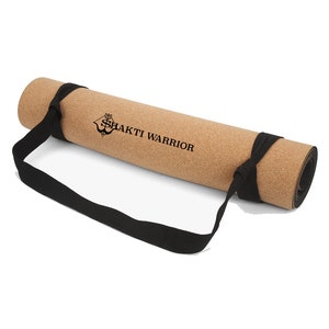May include: A rolled up cork yoga mat with a black carrying strap. The mat has the text "SHAKTI WARRIOR" printed on it.