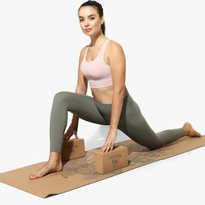 Puede incluir: Una mujer con un sujetador deportivo rosa y leggings verdes est&aacute; haciendo una pose de yoga en una esterilla de yoga de corcho con dos bloques de yoga de corcho. Los bloques tienen el texto "Soul & Body Magic" impreso en ellos.