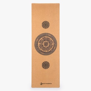 May include: A brown cork yoga mat with three black mandala designs printed on it. The mat has the text "Bhakti Warrior" printed on the bottom.