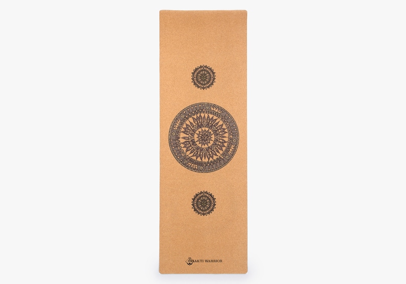 May include: A brown cork yoga mat with three black mandala designs printed on it. The mat has the text "Bhakti Warrior" printed on the bottom.