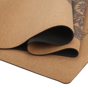 May include: A brown cork yoga mat rolled up, showing the black rubber lining. The mat has a subtle pattern on the surface.