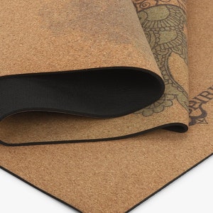 Puede incluir: Una esterilla de yoga de corcho marr&oacute;n con un borde negro y un dise&ntilde;o de mandala verde y marr&oacute;n. La esterilla est&aacute; enrollada y el dise&ntilde;o es visible en el exterior del rollo.