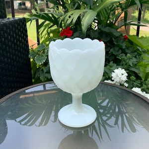 K&ouml;nnte beinhalten: Wei&szlig;e Milchglas-Blumenvase mit gewelltem Rand und Rautenmuster. Die Vase hat einen Sockel.