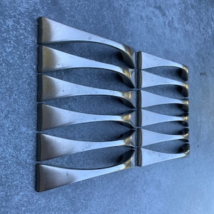 Puede incluir: Conjunto de ocho tiradores de armario plateados con un diseño curvo y moderno.