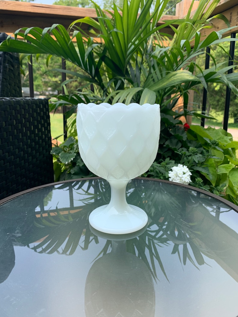 K&ouml;nnte beinhalten: Wei&szlig;e Milchglasvase mit Diamantmuster. Die Vase hat einen breiten, runden Boden und einen hohen, schlanken Stiel.