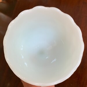 K&ouml;nnte beinhalten: Eine wei&szlig;e Milchglas-Sch&uuml;ssel mit einem gewellten Rand. Die Sch&uuml;ssel ist leer und scheint in gutem Zustand zu sein.