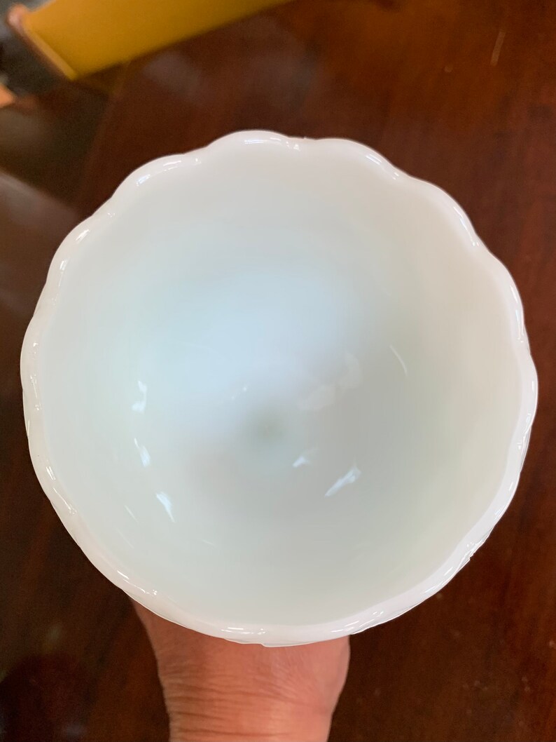 K&ouml;nnte beinhalten: Eine wei&szlig;e Milchglas-Sch&uuml;ssel mit einem gewellten Rand. Die Sch&uuml;ssel ist leer und scheint in gutem Zustand zu sein.