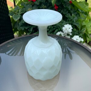 K&ouml;nnte beinhalten: Ein wei&szlig;er Milchglas-Sockel mit einem Diamantenmuster. Der Sockel hat eine breite, flache Oberseite und eine runde Basis.