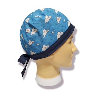 May include: Blue and white patterned surgical scrub hat with a navy blue trim and ties. The hat features a repeating pattern of white clouds on a blue background.